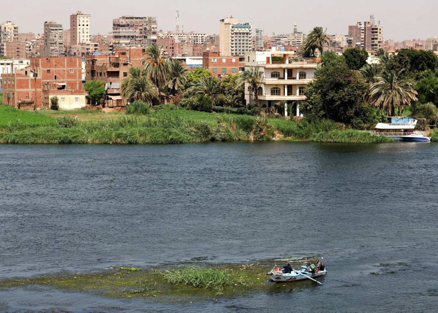 A fisherman travels on a boat with his family during low water levels on the River Nile with crowded residential buildings in the capital city of Cairo, Egypt, August 3, 2026. REUTERS/Amr Abdallah Dalsh