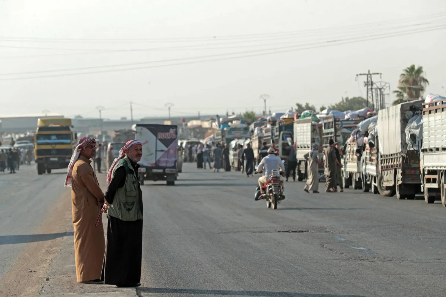 Onlookers stand along the road as Syrian Kurds, who were living in displacement camps in the city of Hasakeh, prepare to head back to the northeastern border town of Ras al-Ain on August 10, 2026. (AFP)
