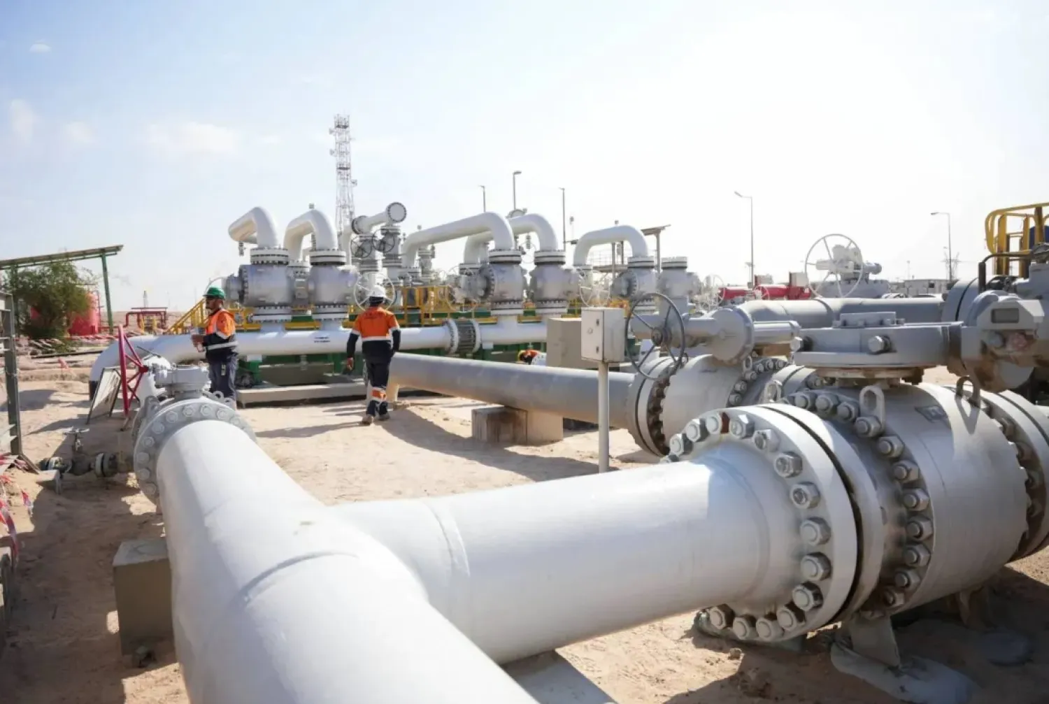 Workers walk across pipelines at the Rumaila oil field in Basra, Iraq (Reuters)