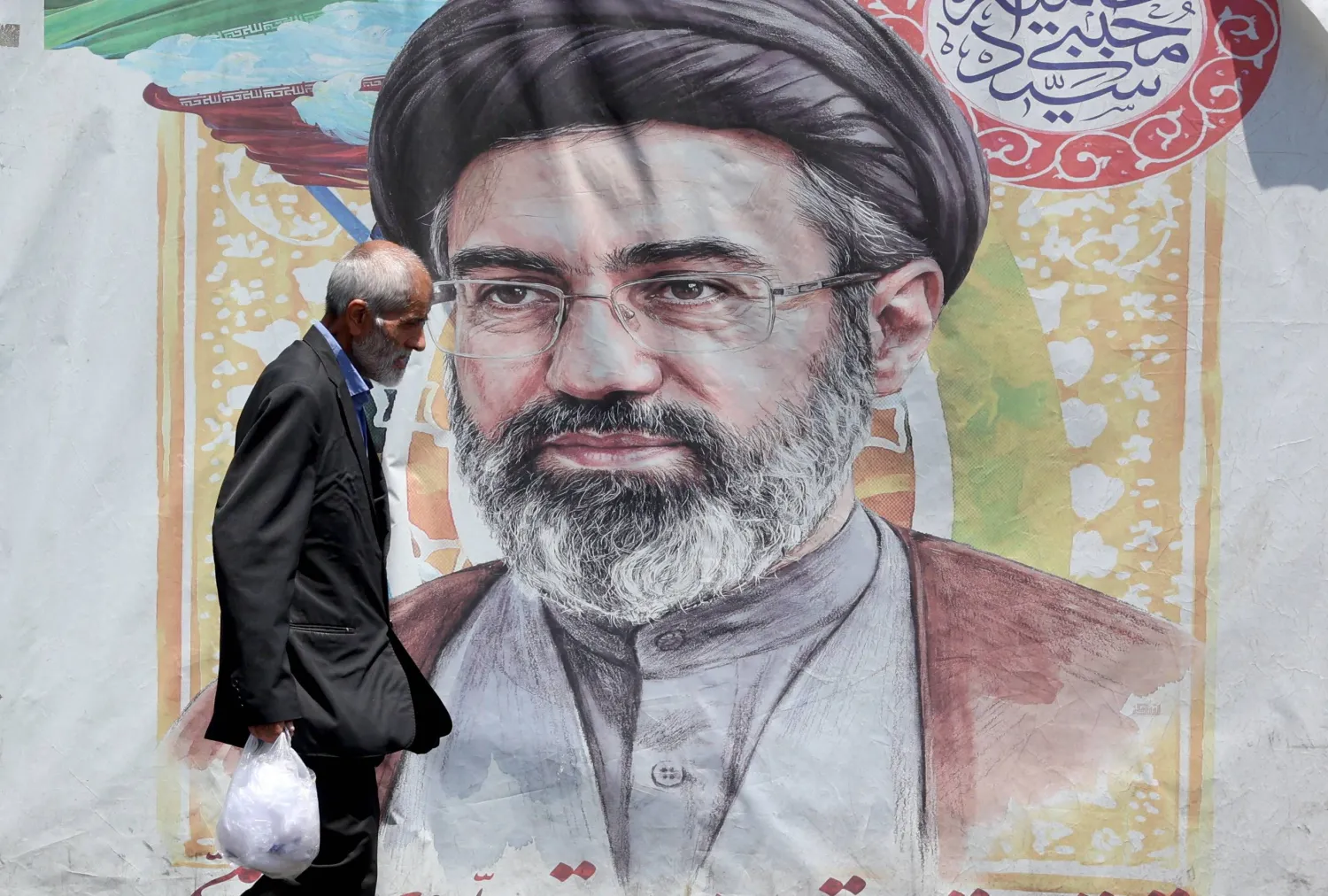 إيراني يمر أمام صورة للمرشد مجتبى خامنئي في طهران غداة توقيع اتفاق إنهاء الحرب مع الولايات المتحدة (إ.ب.أ)