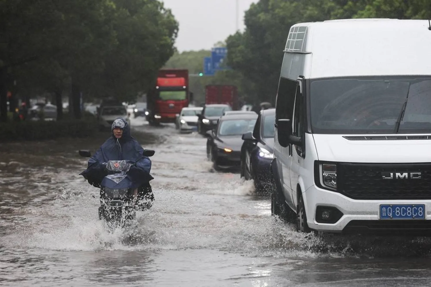 A person rides an electric bike through a flooded street after Typhoon Dolphin brought heavy rain to Shanghai, China, August 10, 2026. (Reuters)