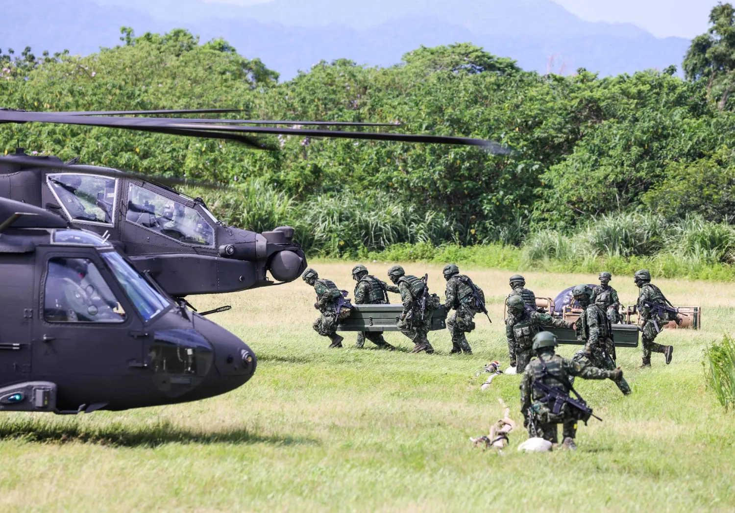 Taiwanese soldiers carry fuel supplies towards AH-64E Apache Guardian and UH-60M Black Hawk helicopters during a refueling drill as part of the annual Han Kuang military exercise in Taoyuan on August 11, 2026. (AFP)