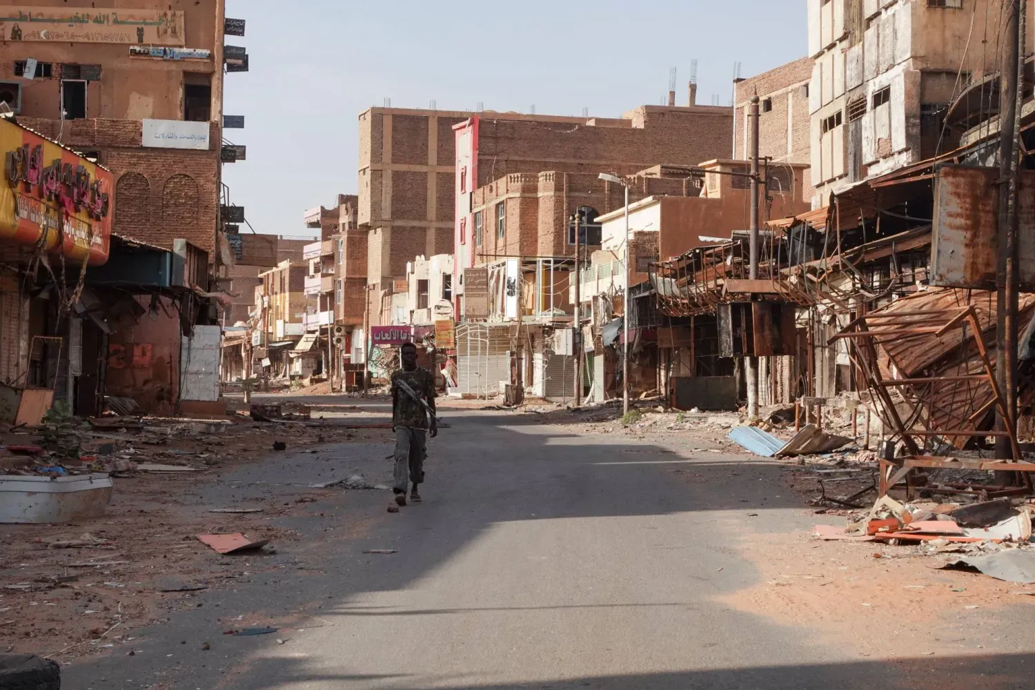 Sudan ordusundan bir asker, Hartum’da savaş nedeniyle hasar görmüş evlerin arasından geçiyor. (Arşiv – Reuters)