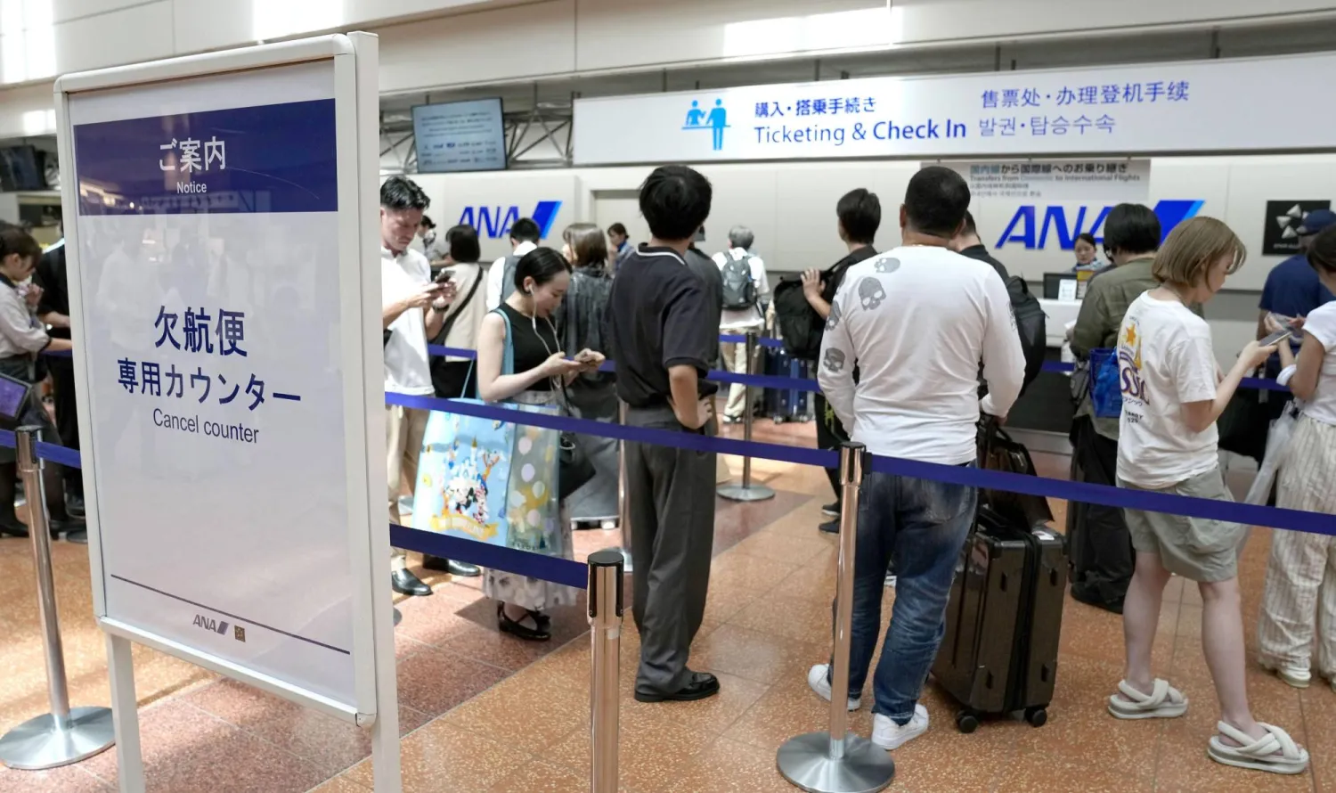  Passengers line up in front of an All Nippon Airways counter at Haneda airport in Tokyo following flight cancellations due to Tropical Storm Chan-hom Tuesday, Aug. 11, 2026. (Katsuya Miyagawa/Kyodo News via AP) 