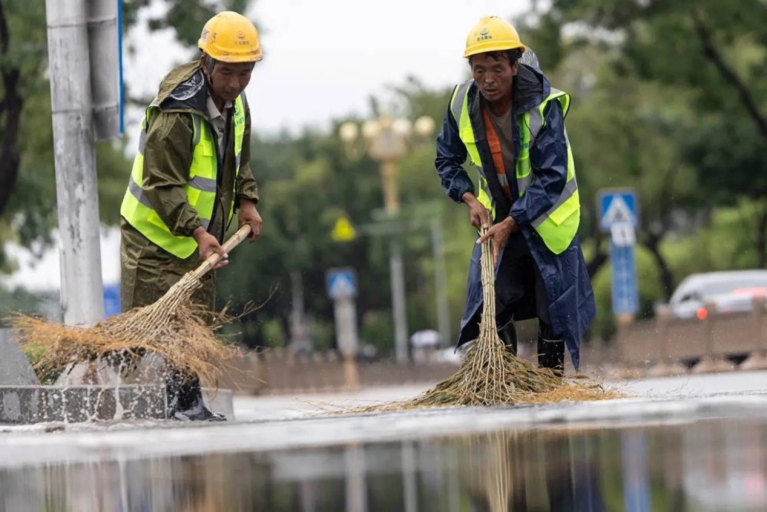 Communal workers sweep water in the street after morning flood caused by flash rain in the wake of typhoon Dolphin, in Changping district of Beijing, China, August 12, 2026. (Reuters)