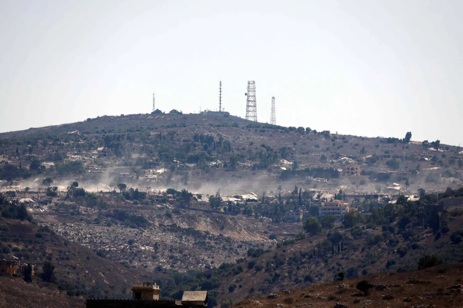 A photograph taken from the southern Lebanese village of Chaqra shows destruction in the border village of Houla, and behind it is what is known as the “Abbad Israeli outpost” on August 11, 2026. (AFP)
