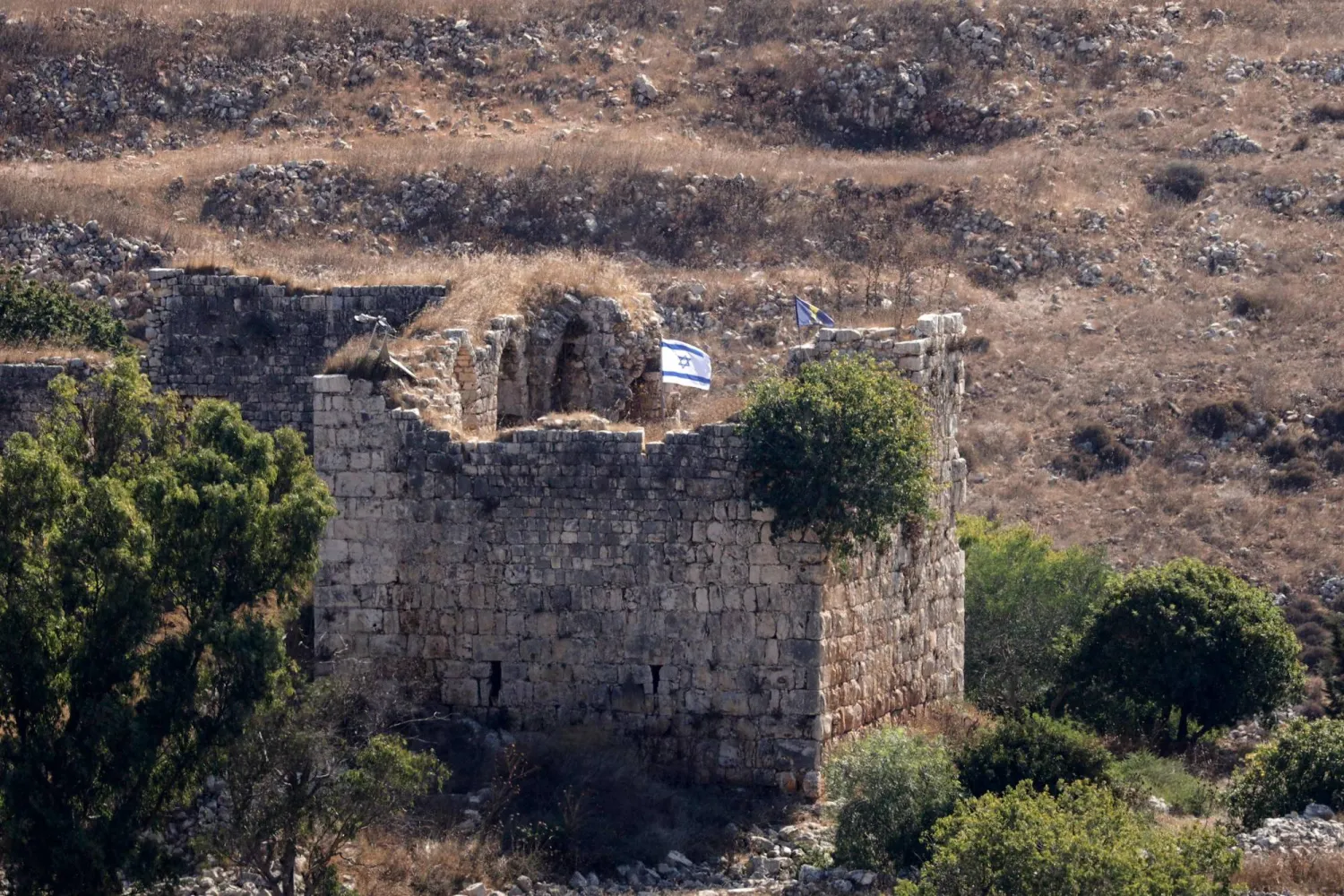 A photograph taken from the southern Lebanese village of Chaqra shows the Israeli flag as it flutters on top of the nearby Crusaders Cital of Doubieh on August 11, 2026. (AFP) 