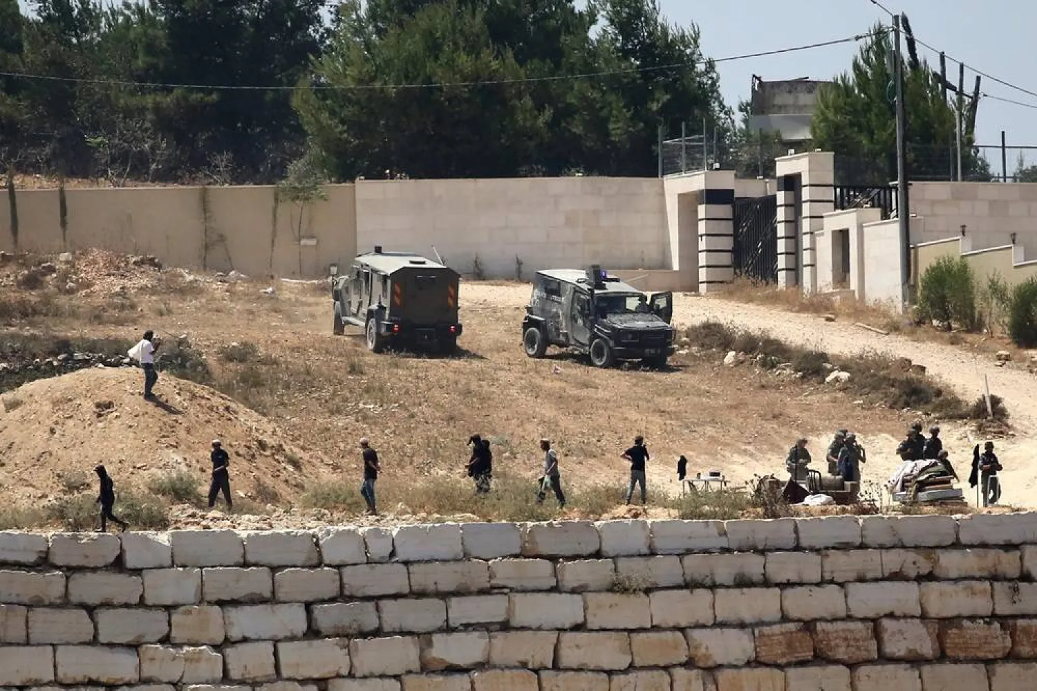  Israeli soldiers stand guard next to settlers in front of Palestinian homes that they have blockaded in the village of Qusra, south of Nablus, in the occupied West Bank, Wednesday, Aug. 12, 2026. (AP) 