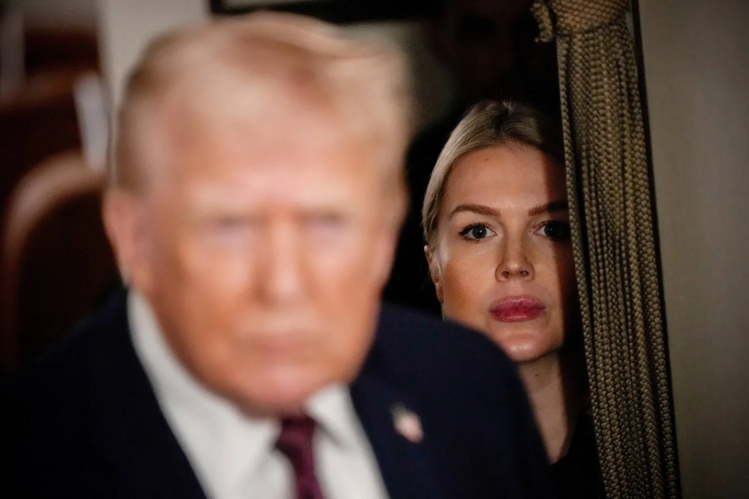 FILE - White House press secretary Karoline Leavitt watches as President Donald Trump speak to reporters while in flight on Air Force One to Joint Base Andrews, Md., Jan. 11, 2026. (AP Photo/Julia Demaree Nikhinson, File)