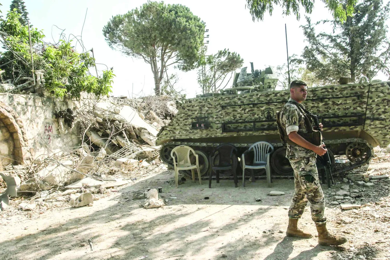 A Lebanese army soldier stands on guard by his armoured vehicle in the southern Lebanese village of Zawtar al-Gharbiyah which was previously badly damaged by the Israeli military on August 8, 2026. (Photo by Mahmoud ZAYYAT / AFP) / 