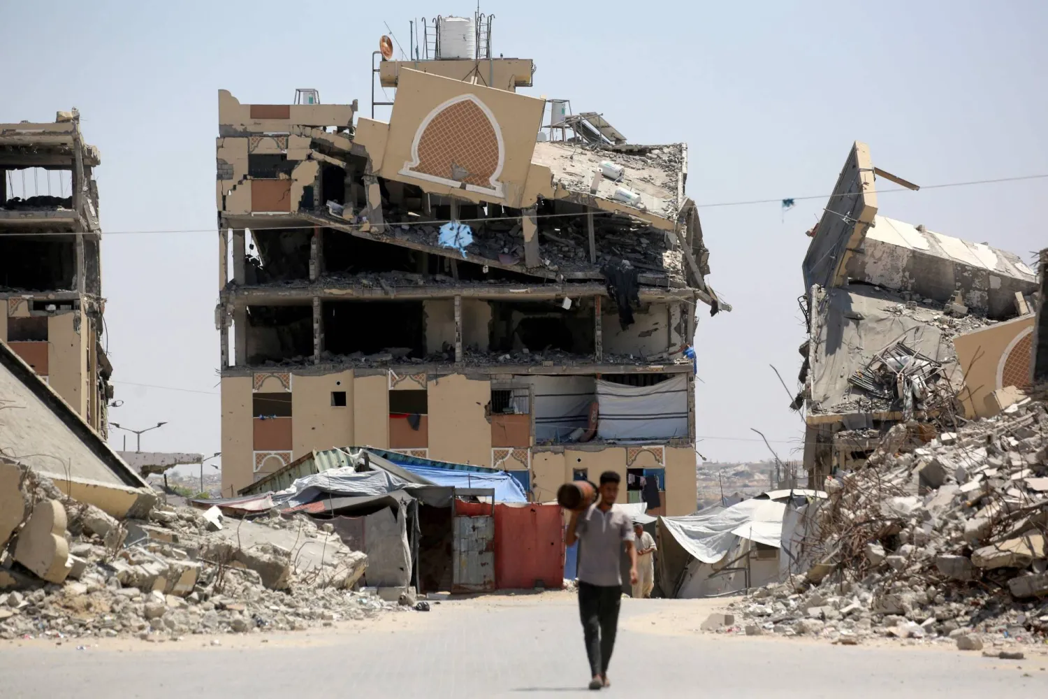 An internally displaced Palestinian man walks past the rubble of buildings destroyed by the Israeli military, in Khan Younis southern Gaza Strip on August 11, 2026. (AFP)