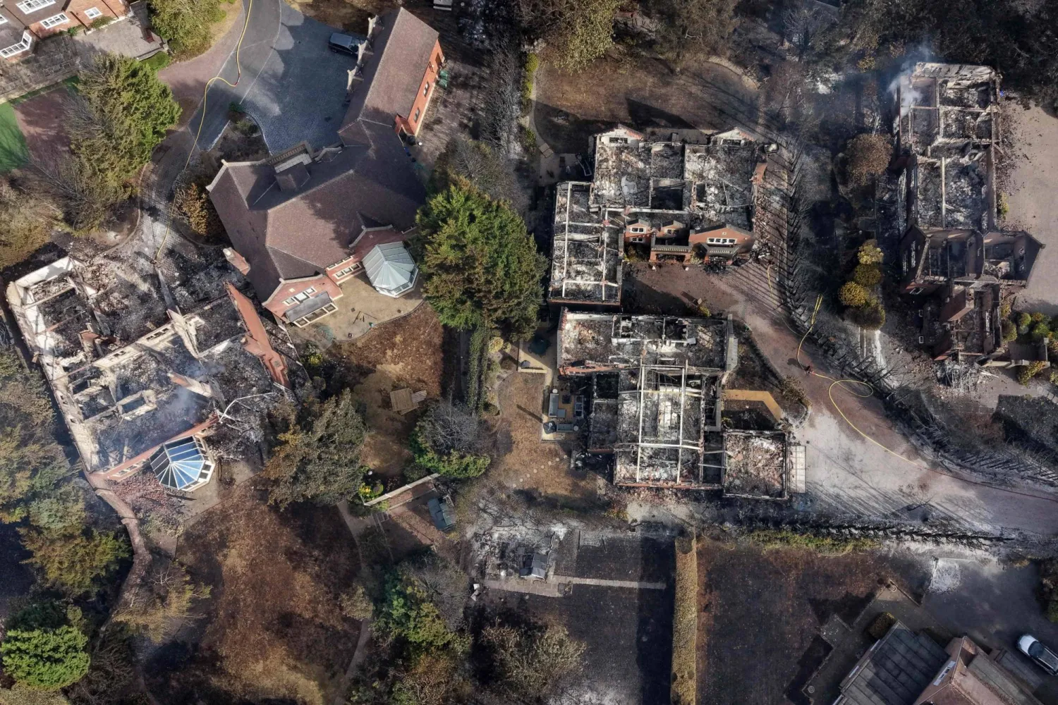 An aerial view shows smoke rising from fire-damaged houses, south of Stourbridge town center in central England on August 14, 2026. (Photo by Darren Staples / AFP)