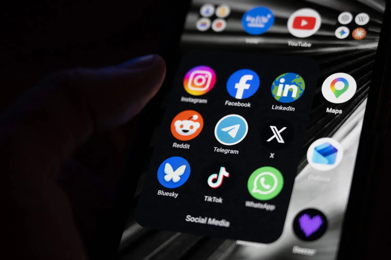 (FILES) This photograph shows a set up smart-phone screen displaying the logo of main social media platforms including Instagram, Facebook, LinkedIn, Reddit, Telegram, X, Bluesky, Tiktok and Whatsapp in Saint-Mande, east of Paris, on April 29, 2026. On August 14, 2026, the French Constitutional Council struck down the ban on social media for under-15s, ruling that this measure constitutes "a disproportionate infringement" of their freedom of expression. (Photo by Martin LELIEVRE / AFP)