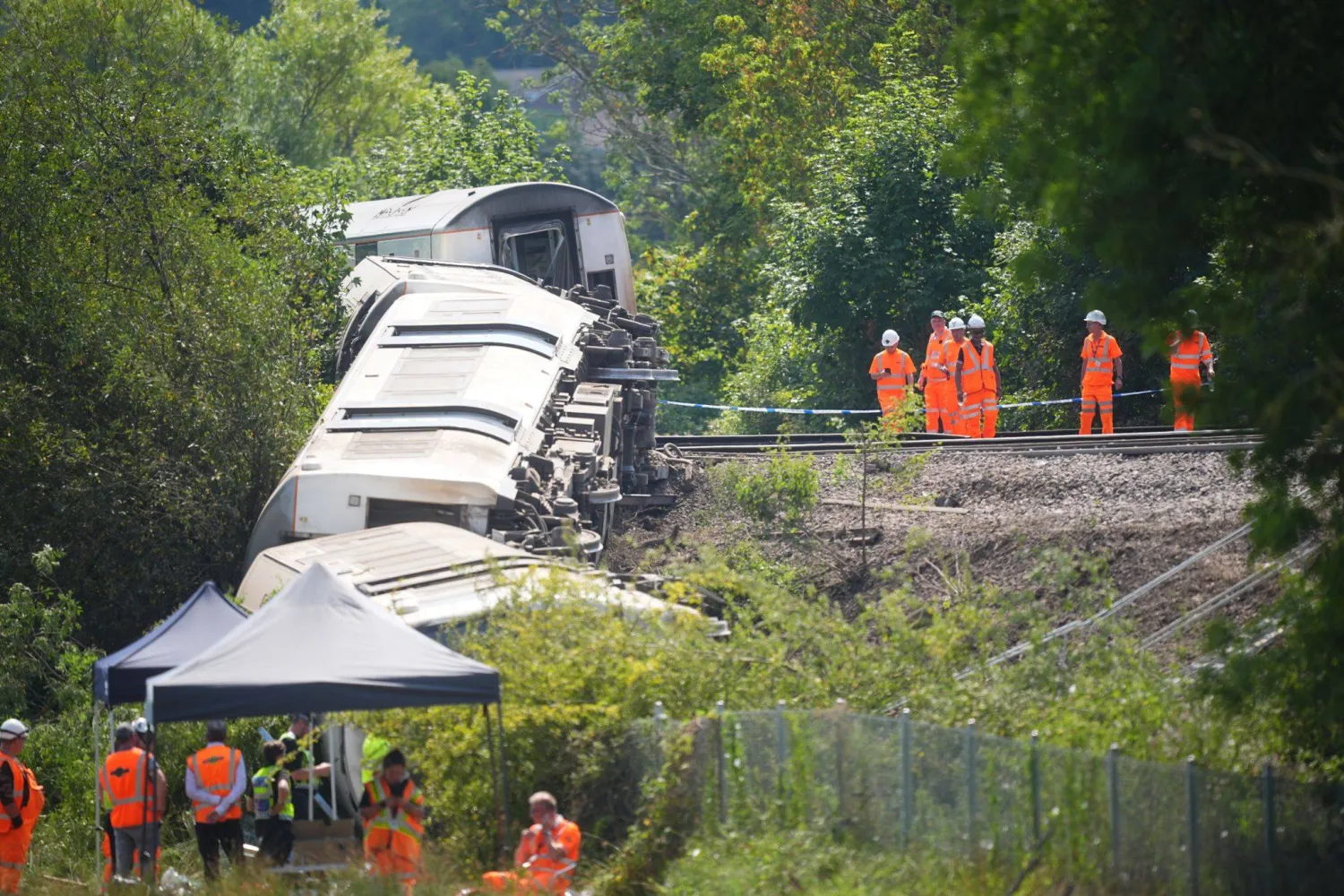 14 August 2026, United Kingdom, Lewes: Rail workers and police officers investigate at the scene where a train with around 150 people on board derailed near Lewes railway station in East Sussex on Thursday. Photo: James Manning/PA Wire/dpa