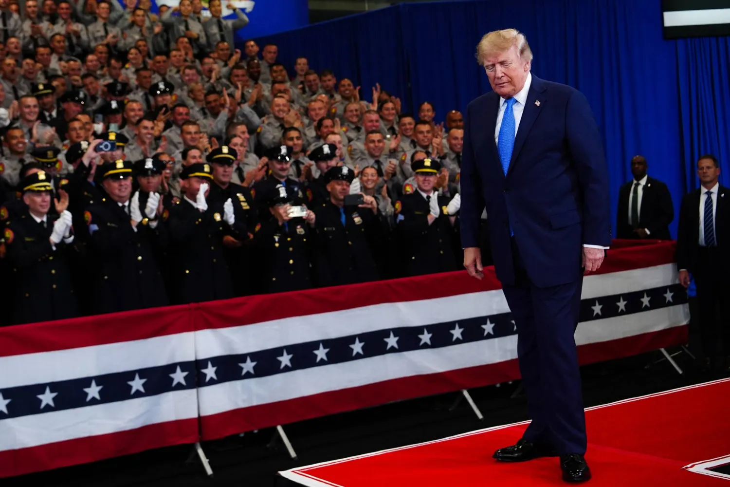Police officers applaud as President Donald Trump arrives to speak at the David Mack Center for Training and Intelligence, Friday, Aug. 14, 2026, in Garden City, N.Y. (AP Photo/Julia Demaree Nikhinson)