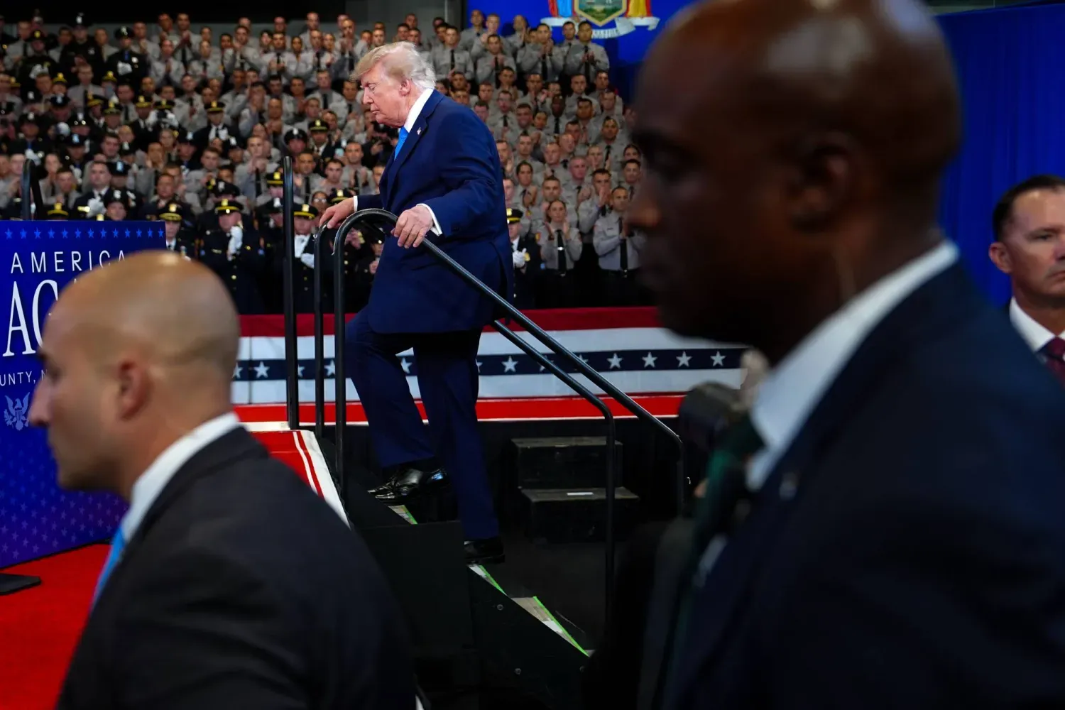 Trump, New York'taki David Mack İstihbarat ve Eğitim Merkezi'nde sahneye doğru yürürken Gizli Servis ajanları teyakkuzda (AP)