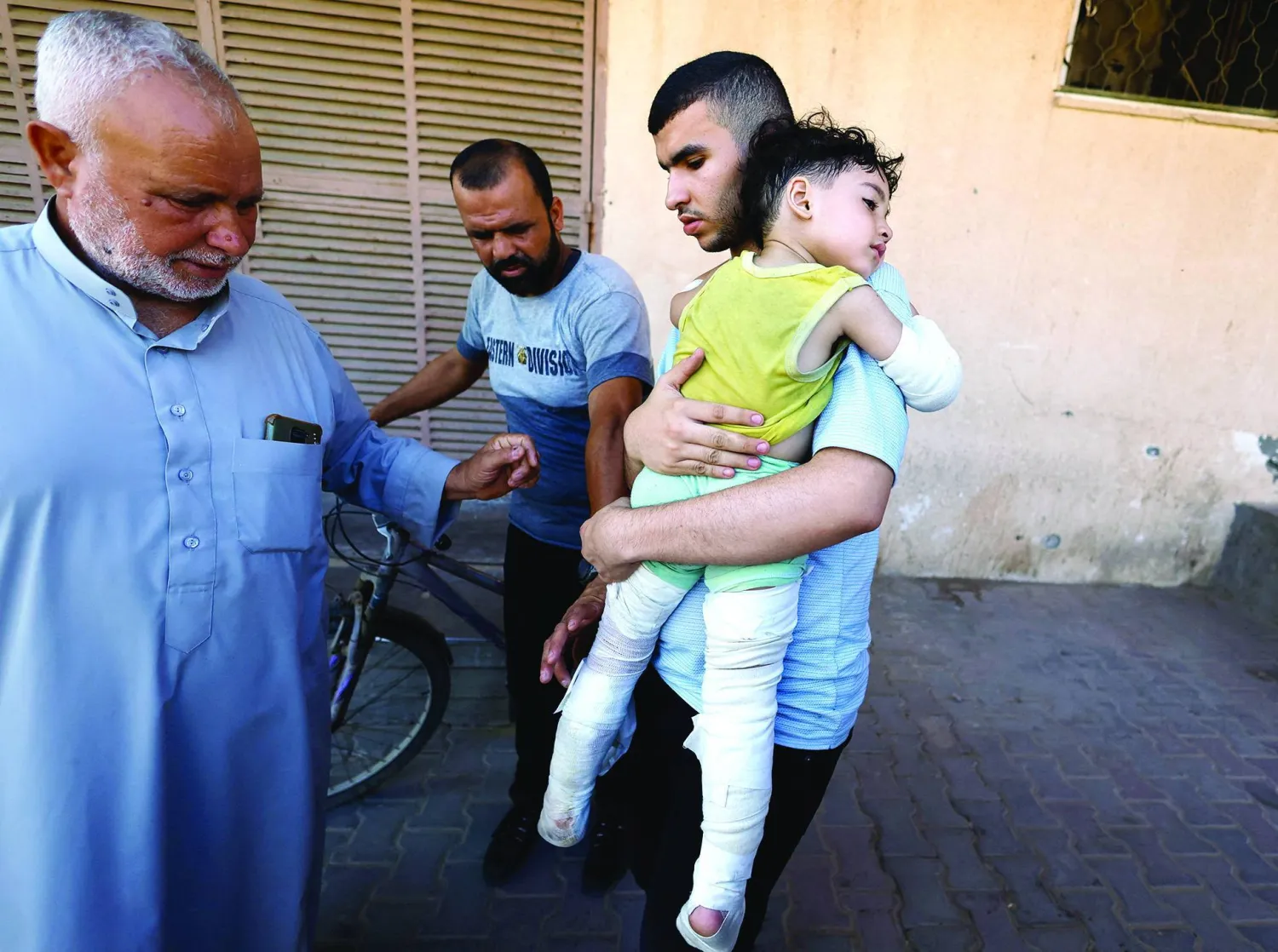 A Palestinian carries a child wounded in an Israeli strike that killed the child’s parents at Al-Aqsa Martyrs Hospital in Deir al-Balah, central Gaza Strip, July 15, 2026 (Reuters) 