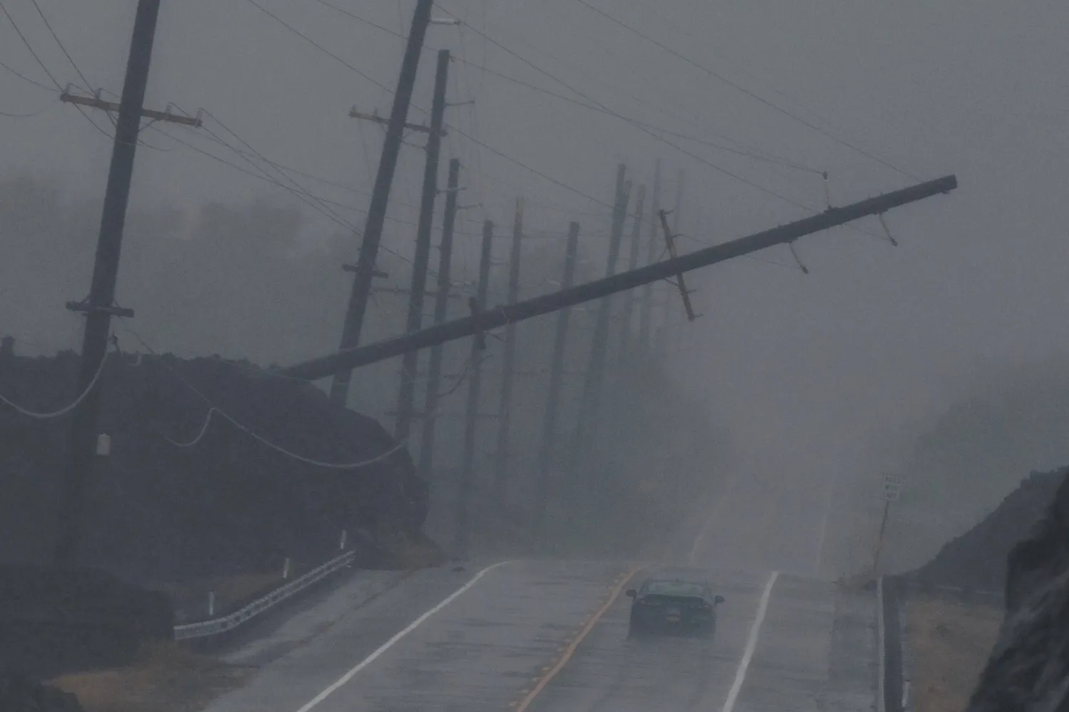  A vehicle drives near a downed utility pole dangling above Mamalahoa Highway during Hurricane Lala near Ocean View, Hawaii, Saturday, Aug. 15, 2026. (Stephen Lam/San Francisco Chronicle via AP) 