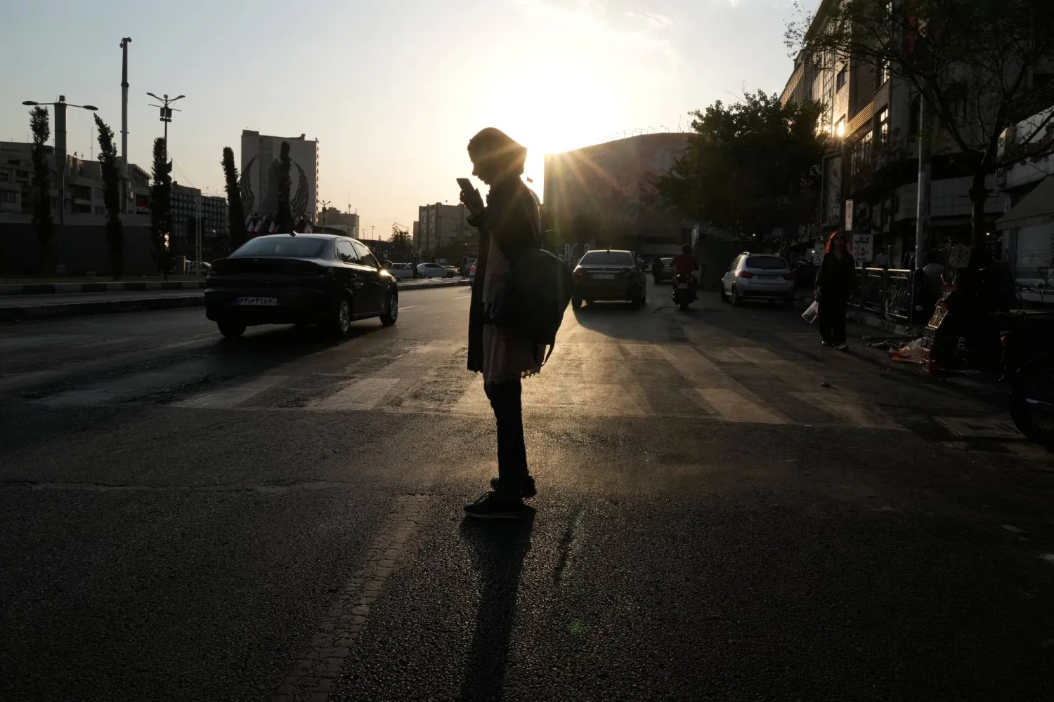 A woman is silhouetted against the sun as she checks her cellphone at Revolution square in downtown Tehran, Iran, Saturday, Aug. 15, 2026. (AP) 