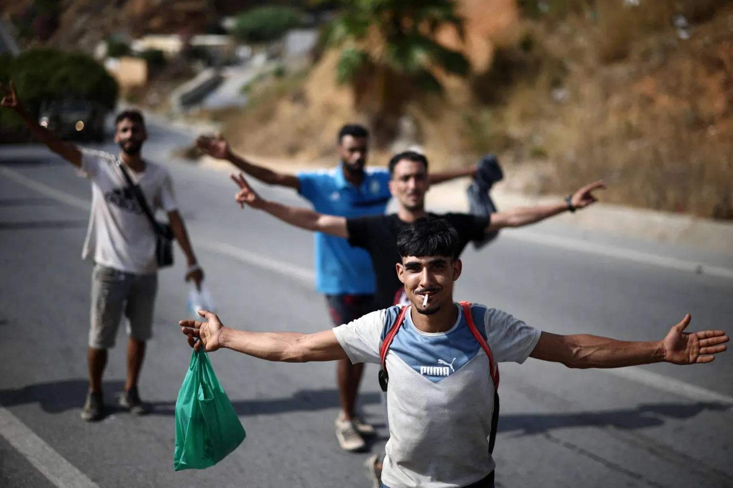 TOPSHOT - Migrants pose for a picture while being escorted to the Ceuta-Morocco border in the Spanish North African enclave of Ceuta on August 1, 2026. (Photo by Henry NICHOLLS / AFP)