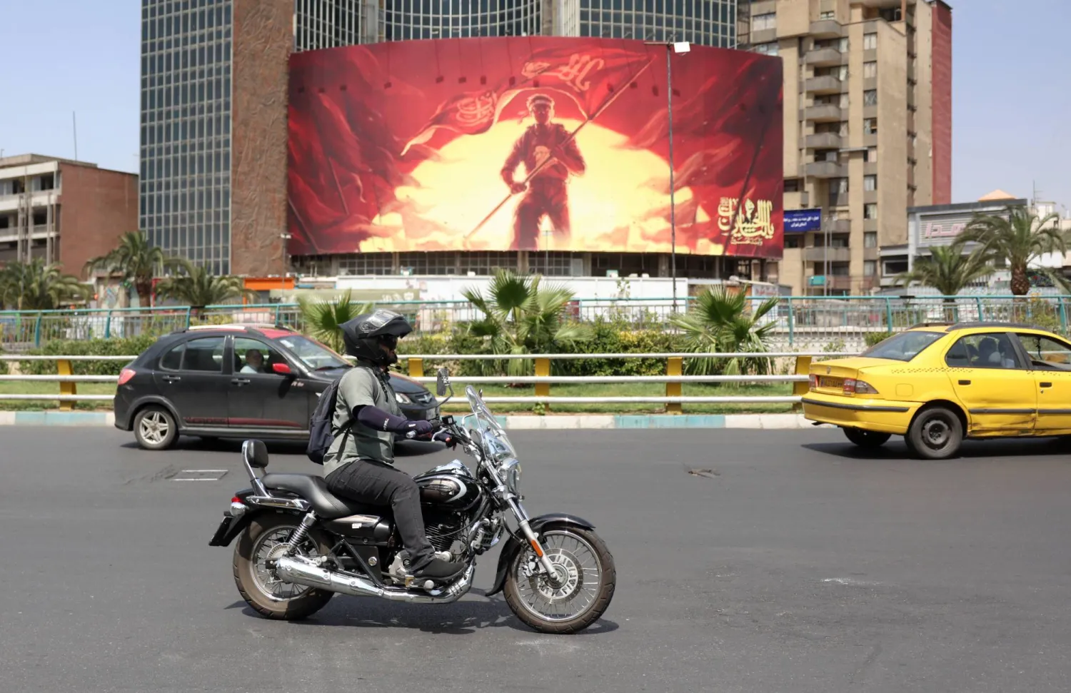An Iranian rides a motorbike past a political billboard displayed at the Valiasr square in Tehran, Iran, 17 August 2026. (As mandated by Iran's Directorate General for Foreign Media)