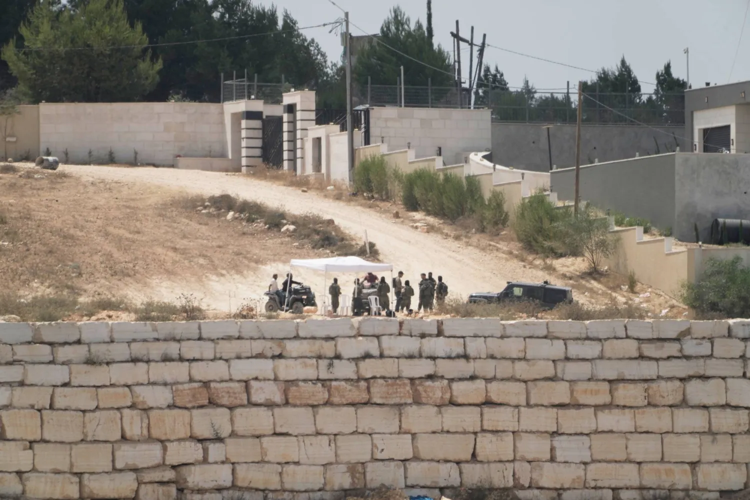 مستوطنون إسرائيليون أمام منازل فلسطينية محاصرة في قرية قصرة بالضفة الغربية المحتلة جنوب نابلس (أ.ب)