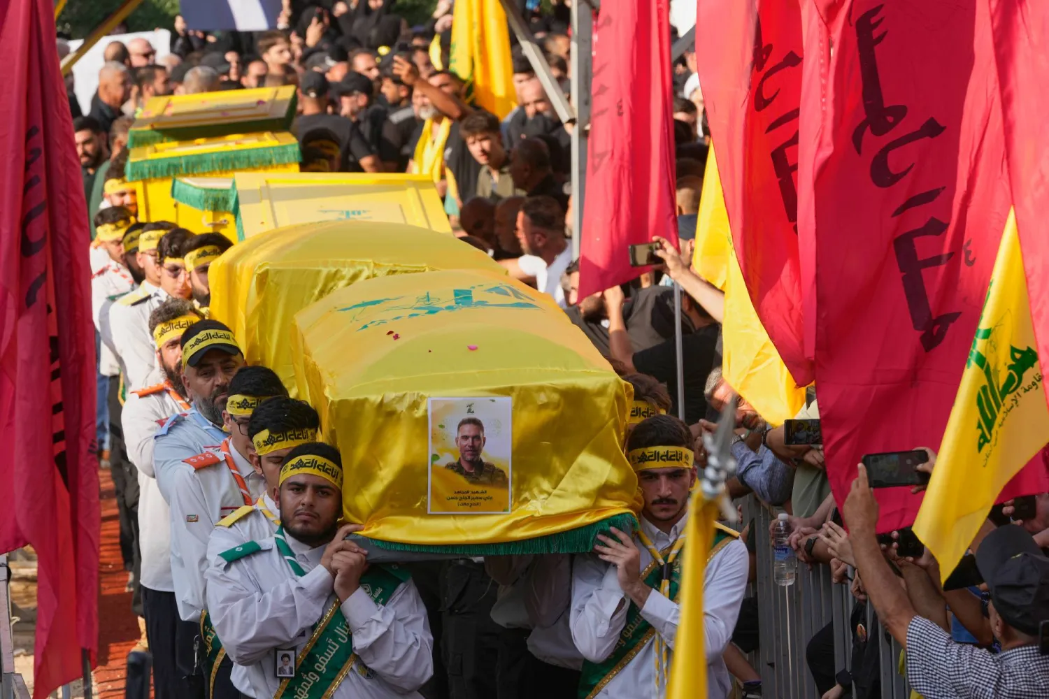يحمل عناصر من كشافة «حزب الله» نعوش القيادي علي الحاج حسن وزوجته وأطفاله الأربعة الذين قُتلوا السبت في غارة إسرائيلية وذلك خلال موكب تشييعهم بالضاحية الجنوبية يوم الأحد (أ.ب)