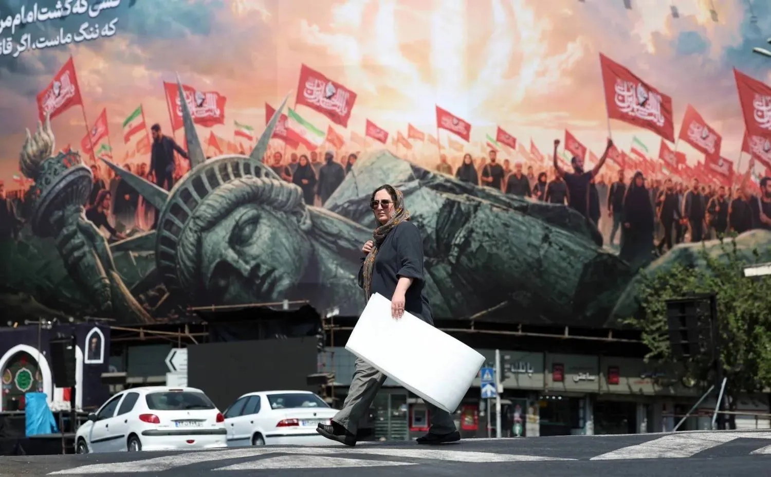 An Iranian woman walks past an anti-US billboard in Enghelab Square in central Tehran (EPA) 