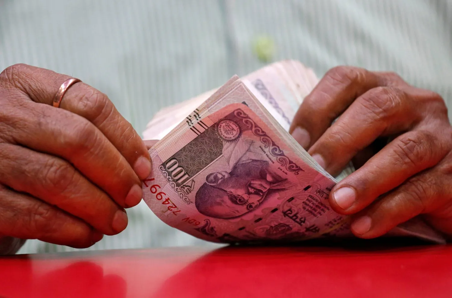 رجل يعدّ أوراقاً نقدية هندية داخل متجر في مومباي (رويترز)