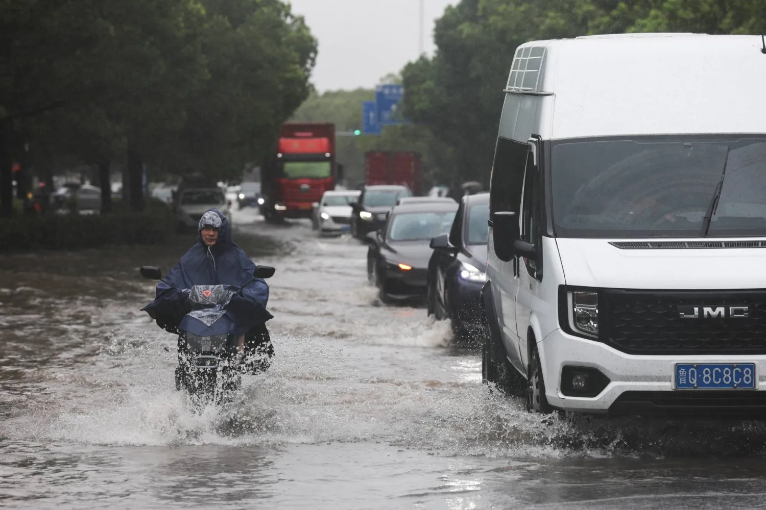A person rides an electric bike through a flooded street after Typhoon Dolphin brought heavy rain to Shanghai, China, August 10, 2026. (Reuters)