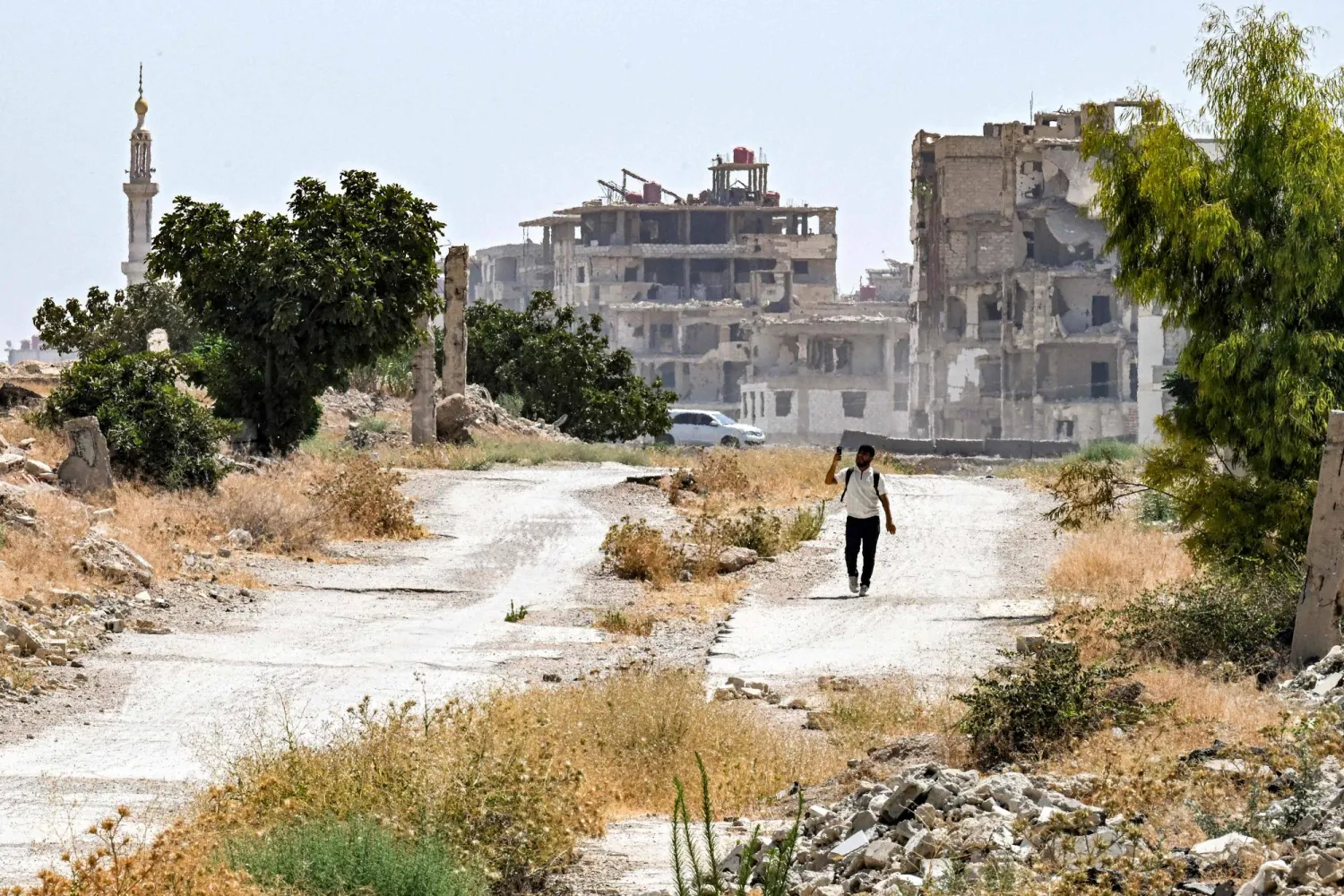 A man walks past heavily-damaged and destroyed buildings in the Jobar suburb northeast of Damascus on August 12, 2026. (Photo by LOUAI BESHARA / AFP)
