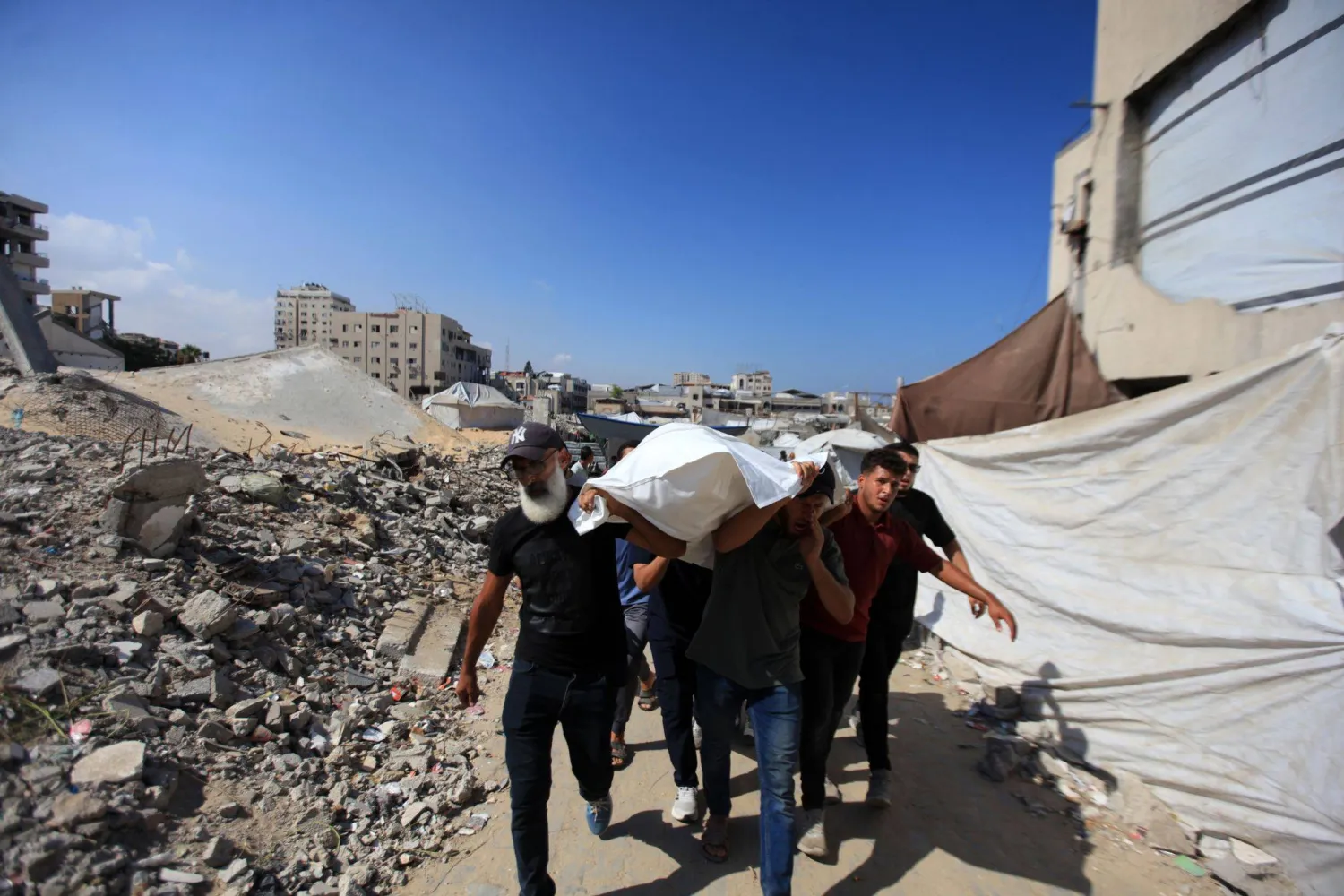 السكان يشيعون الفلسطينيين الذين سقطوا في غارة إسرائيلية على ميناء مدينة غزة الثلاثاء (د.ب.أ)