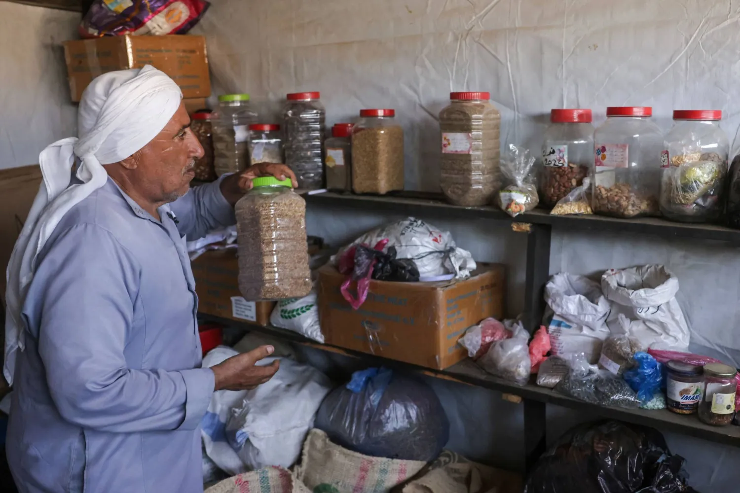 Salem Muhanna, who manages the Al Qarara Seed Bank with support from the International Committee of the Red Cross (ICRC), prepares to stack a container with seeds at the bank, in Deir el-Balah, central Gaza Strip on August 11, 2026. (Photo by Bashar Taleb / AFP)