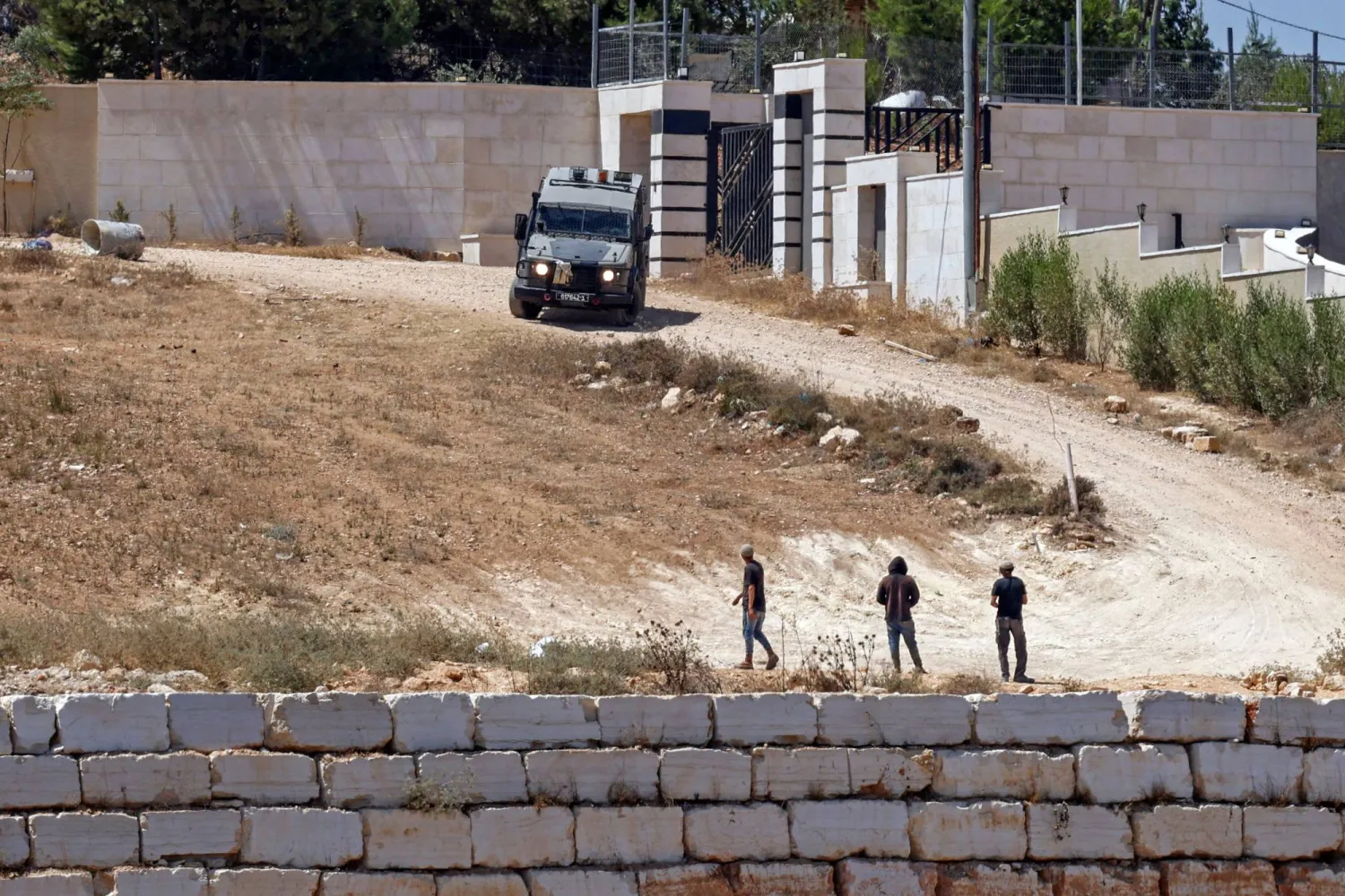 An Israeli military vehicle patrols near to the settlers in front of the Palestinian houses in the village of Qusra, south of Nablus, in the occupied West Bank, on August 13, 2026. (Photo by Zain JAAFAR / AFP)
