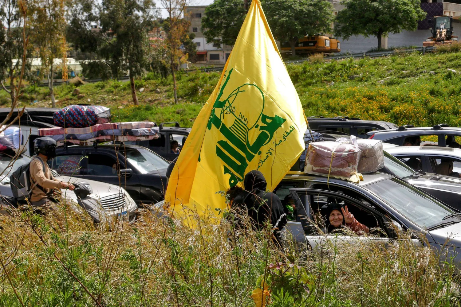 17 April 2026, Lebanon, Jiyyeh: A displaced Lebanese woman flashes the victory sign and displays Hezbollah and Iranian flags as they drive along the highway linking Beirut to southern Lebanon in the Jiyyeh area. (dpa)