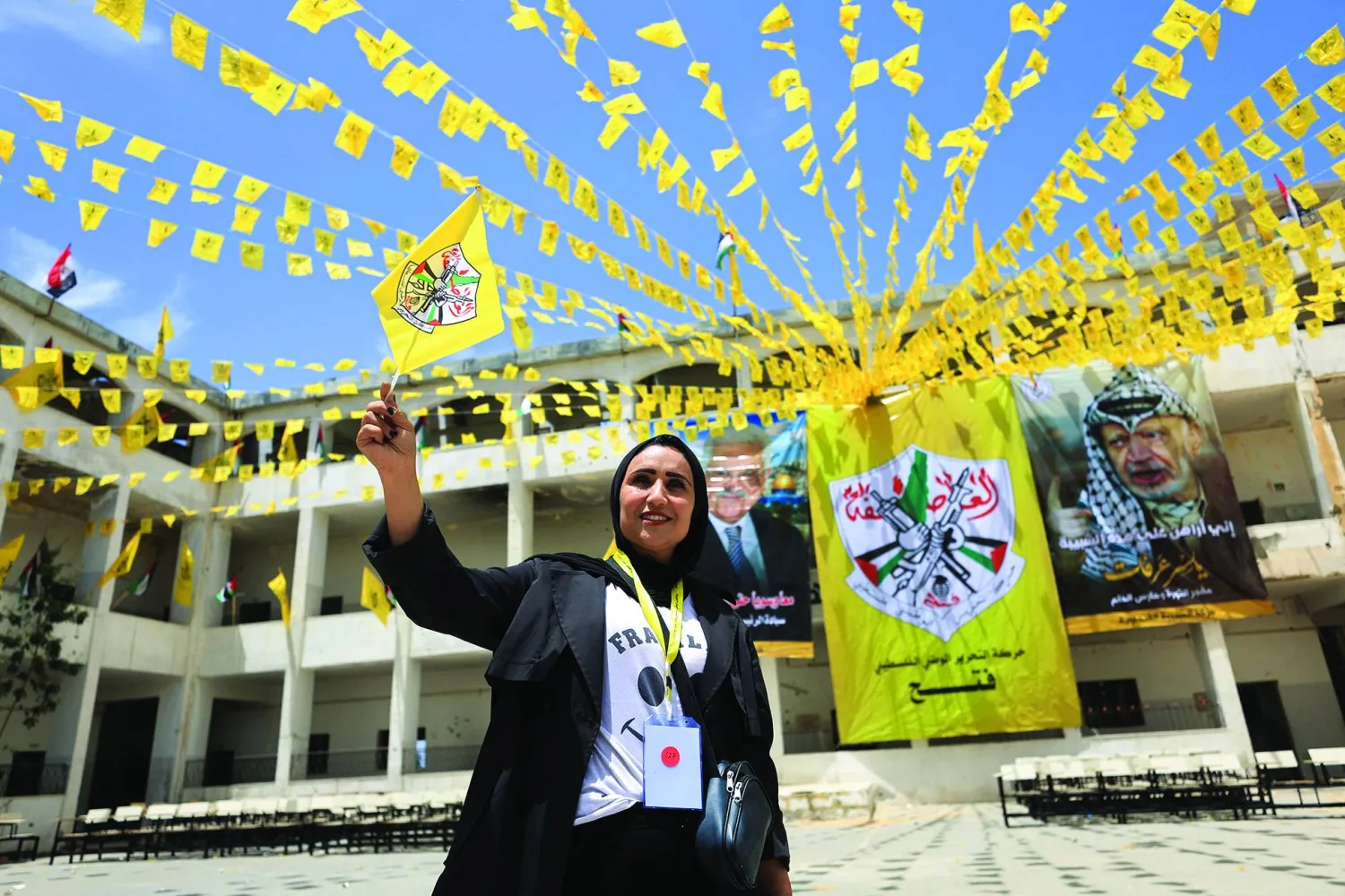 فلسطينية تلوّح بعَلم «فتح» خلال مشاركتها في المؤتمر الثامن للحركة بجامعة الأزهر بمدينة غزة 14 مايو 2026 (رويترز)
