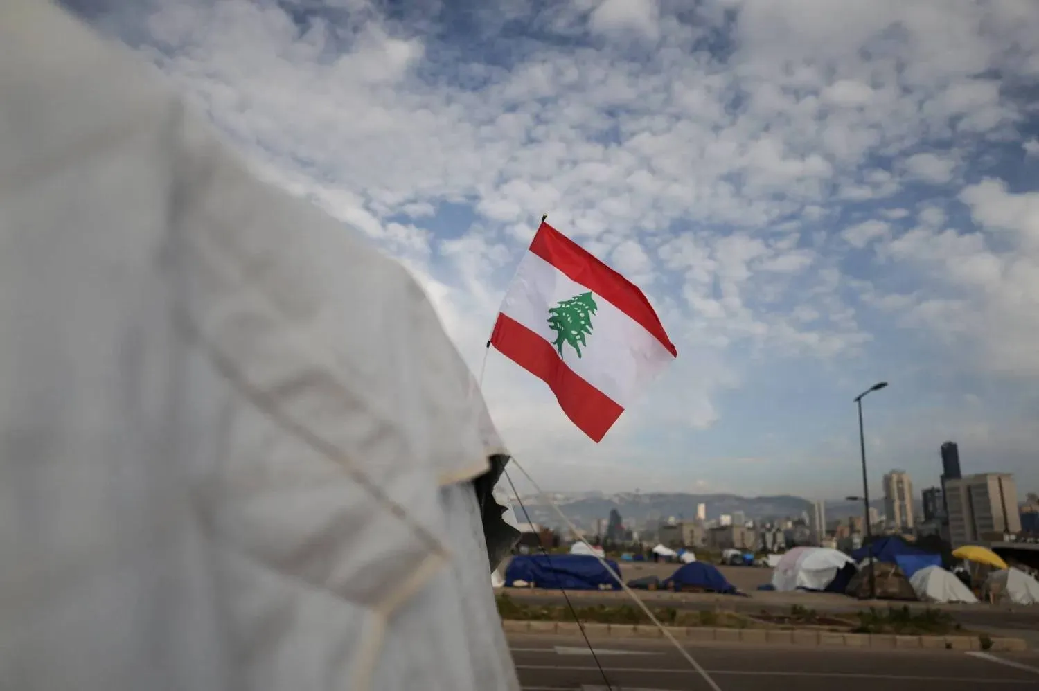 علم لبنان يرفرف على خيمة نازحين بمخيم مؤقت في بيروت (رويترز)