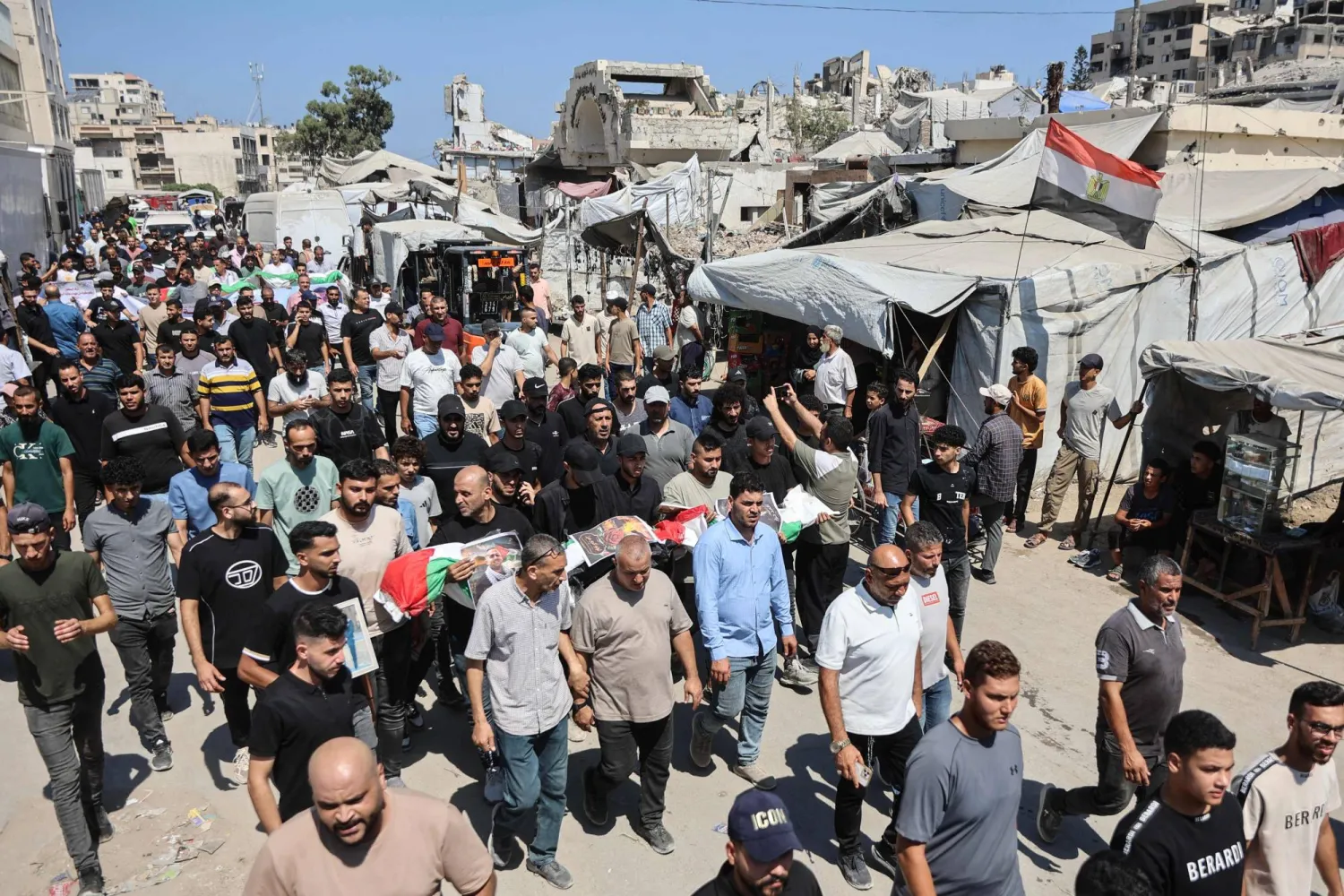 Mourners carry flag-draped body bags containing the remains of Palestinians killed in Israeli strikes during the war with Hamas and recently recovered from the rubble, during a mass funeral in Gaza City on August 20, 2026. (AFP)