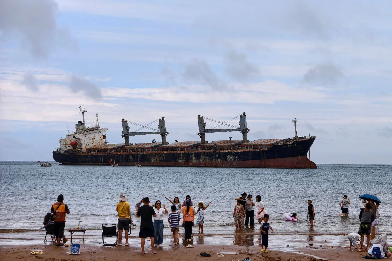 Beachgoers view and take photos of the Panamanian-registered bulk carrier ship Blueways, which ran aground following a typhoon in September 2022 off the coast of Weihai, in eastern China's Shandong province on August 21, 2026. (Photo by CN-STR / AFP) 