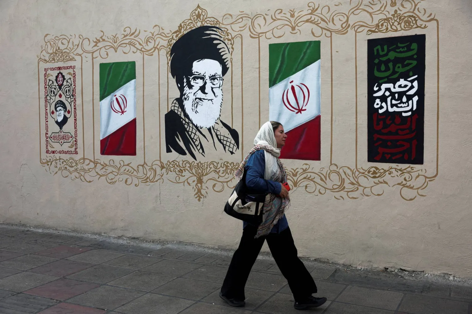 FILE PHOTO: A woman walks by a mural depicting Iran's late Supreme Leader Ali Khamenei, on a street in Tehran, Iran, August 13, 2026. Majid Asgaripour/WANA (West Asia News Agency) via REUTERS 