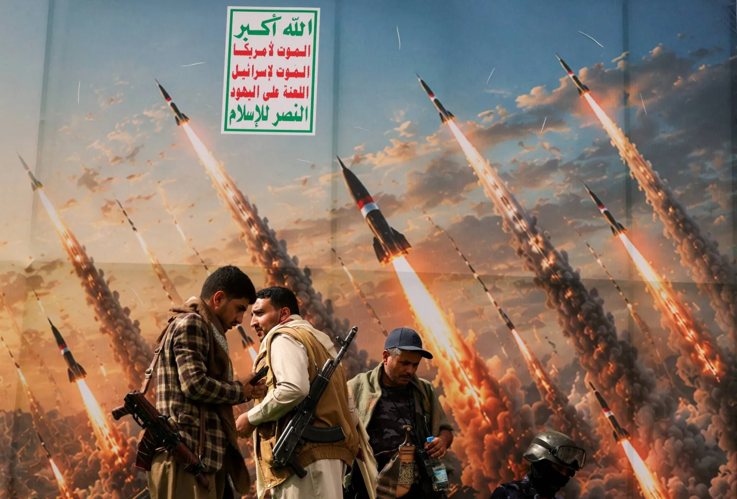 صورة دعائية وضعها الحوثيون خلفية على منصة في صنعاء تُظهر إطلاق مجموعة من الصواريخ (رويترز)
