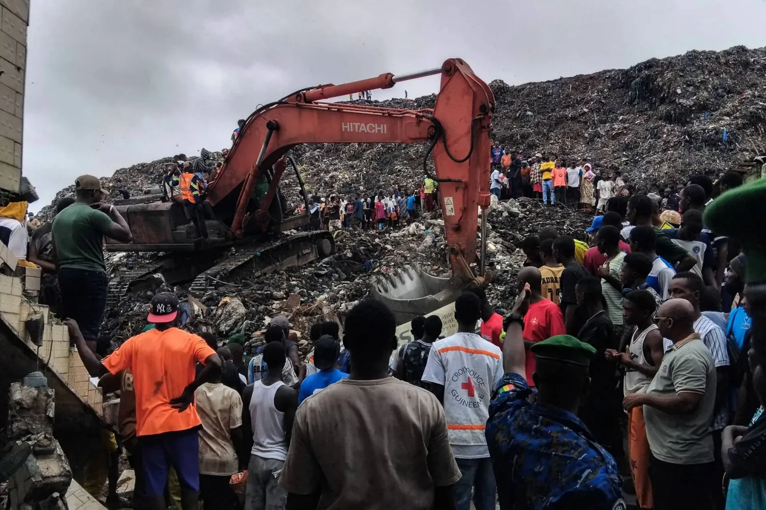 Residents and rescuers use an excavator to search for bodies after a landslide struck the Dar es Salaam dumpsite overnight in Conakry on August 23, 2026. (Photo by AFP)