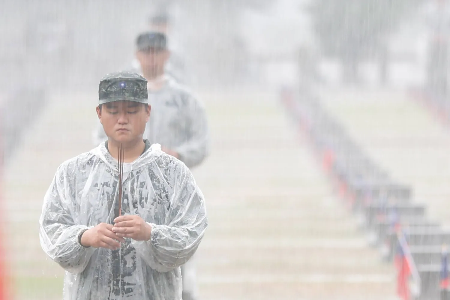 Taiwanese soldiers offer prayers in heavy rain next to the tombstones of fallen soldiers during a ceremony marking the 68th anniversary of the August 23rd artillery battle between Taiwan and China, in Kinmen, Taiwan, 23 August 2026. (EPA)