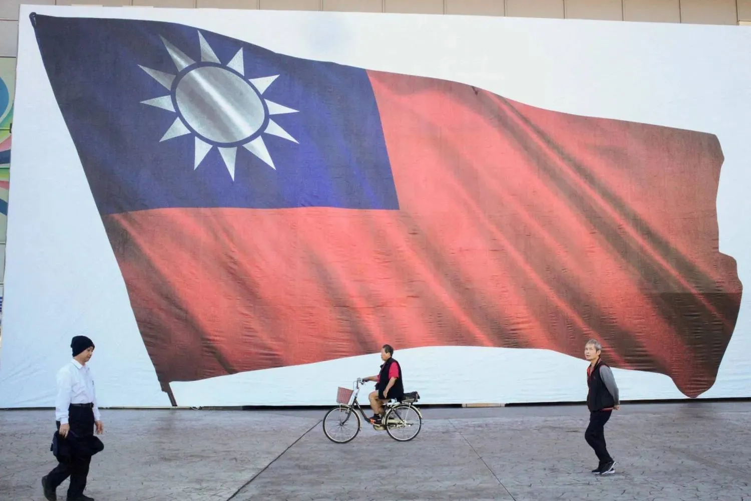 People walk past a Taiwanese flag in New Taipei City on January 13, 2024. (AFP) 