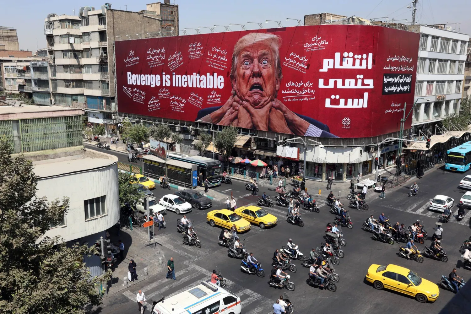 إيرانيون يقودون سياراتهم بالقرب من لوحة إعلانية مناهضة لترمب في طهران (إ.ب.أ)