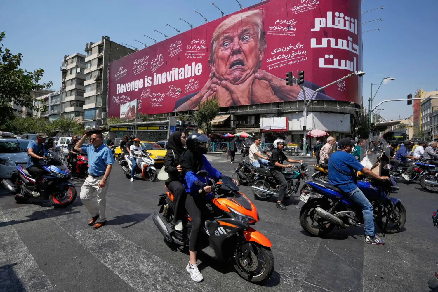 Motorcyclists pass a billboard depicting US President Donald Trump with hands around his neck beneath the words "Revenge is inevitable" in Tehran, Iran, Monday, Aug. 24, 2026. (AP Photo/Vahid Salemi)