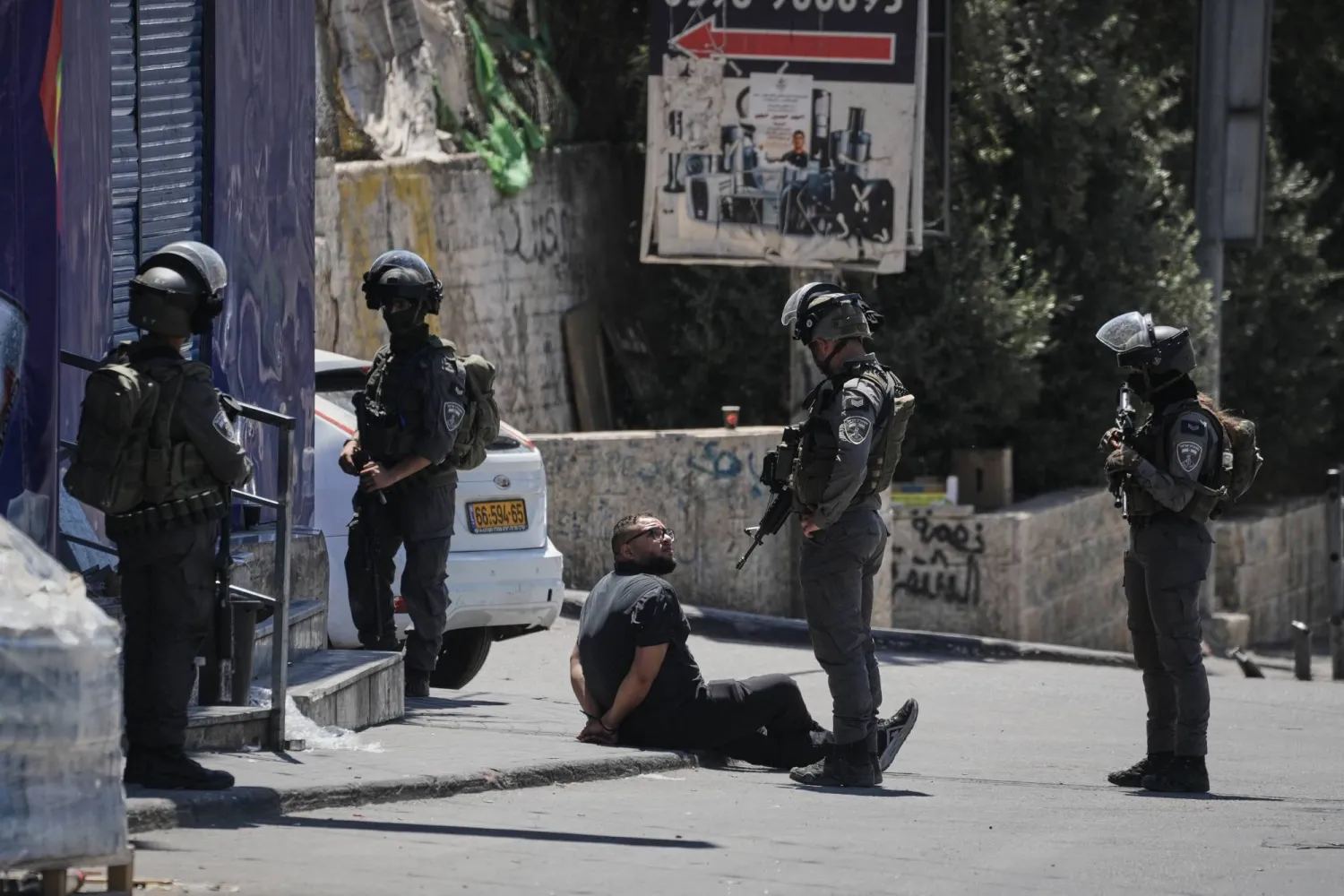 رجل فلسطيني مكبل اليدين يُحتجز من قبل ضباط شرطة الحدود الإسرائيلية خلال عملية للجيش في مخيم قلنديا للاجئين في الضفة الغربية (أ.ب)