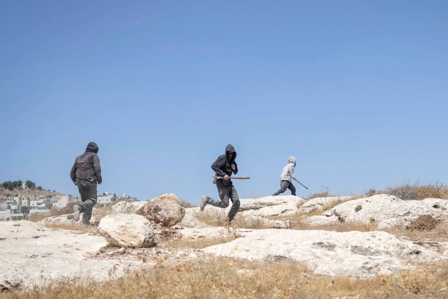  Israeli settlers, holding sticks, arrive to confront left-wing activists at an Israeli outpost in the Israeli-occupied Palestinian village of Jannatah, south of Bethlehem, on August 25, 2026. (AFP)