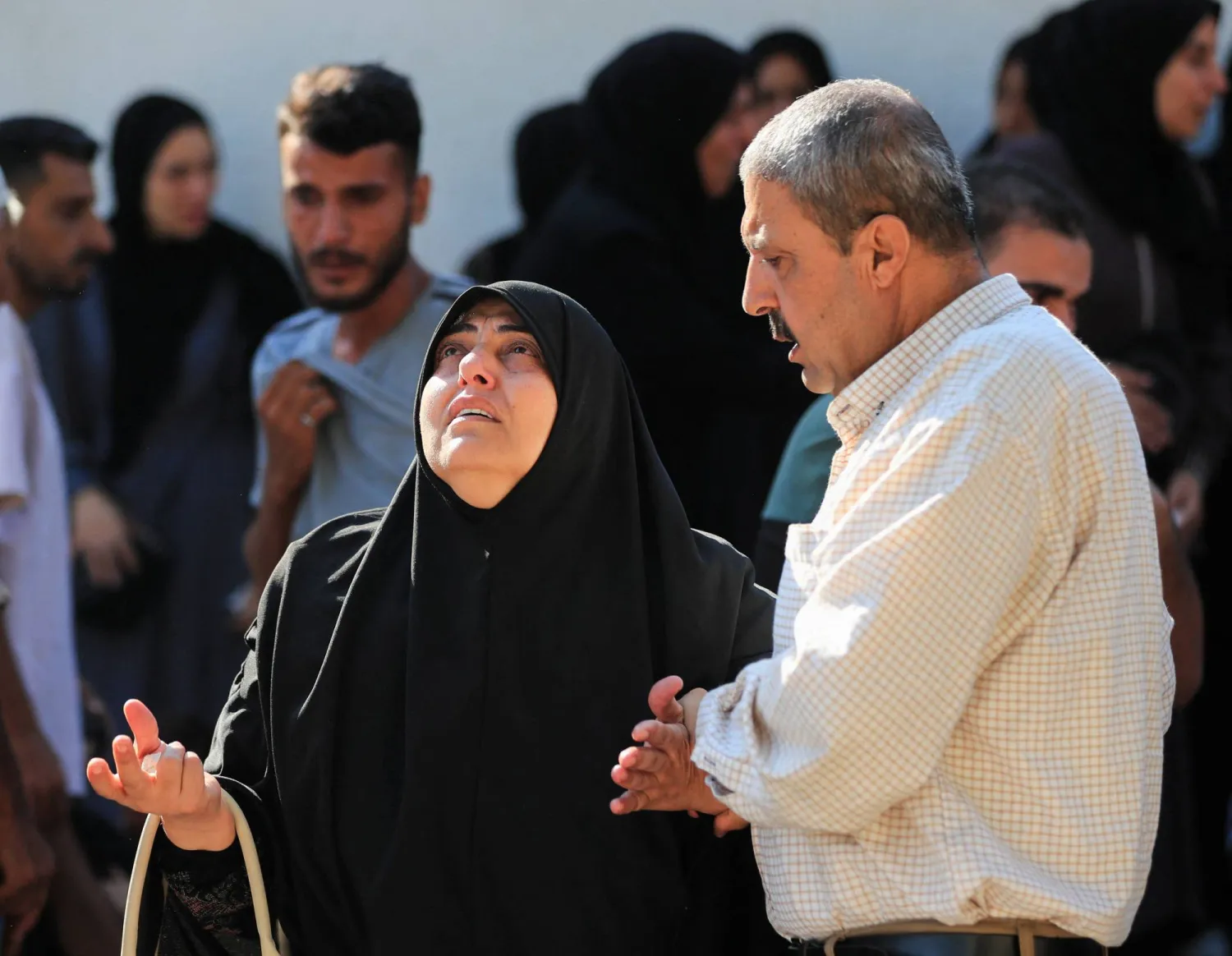 رجل يواسي امرأة ثكلى خلال جنازة فلسطينيين قُتلوا في غارات إسرائيلية في مدينة غزة يوم الأربعاء (رويترز)