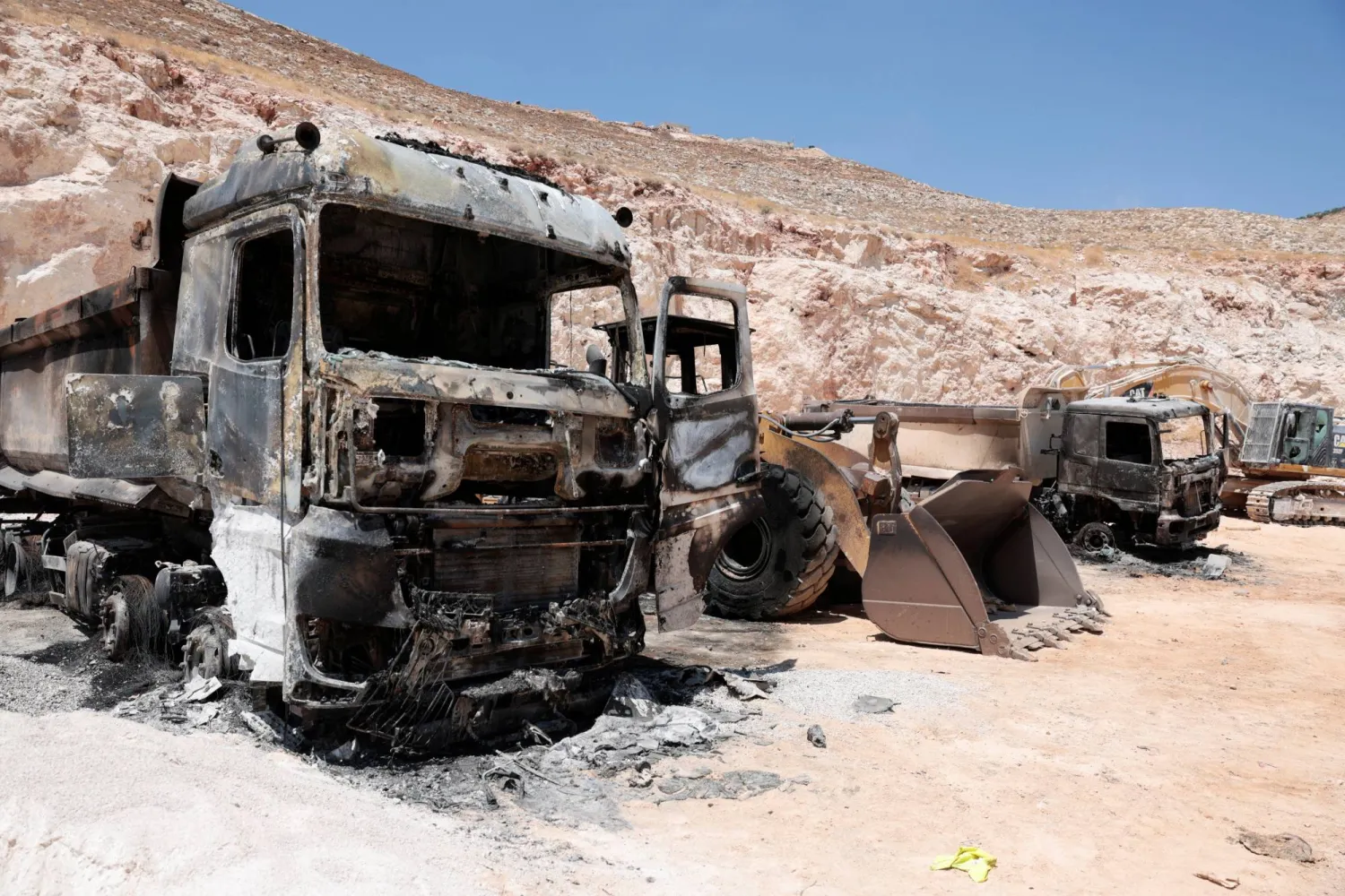 معدات ثقيلة محترقة في محجر فلسطيني بعد هجمات شنّها مستوطنون قرب رام الله بالضفة الغربية يوم الاثنين (رويترز)